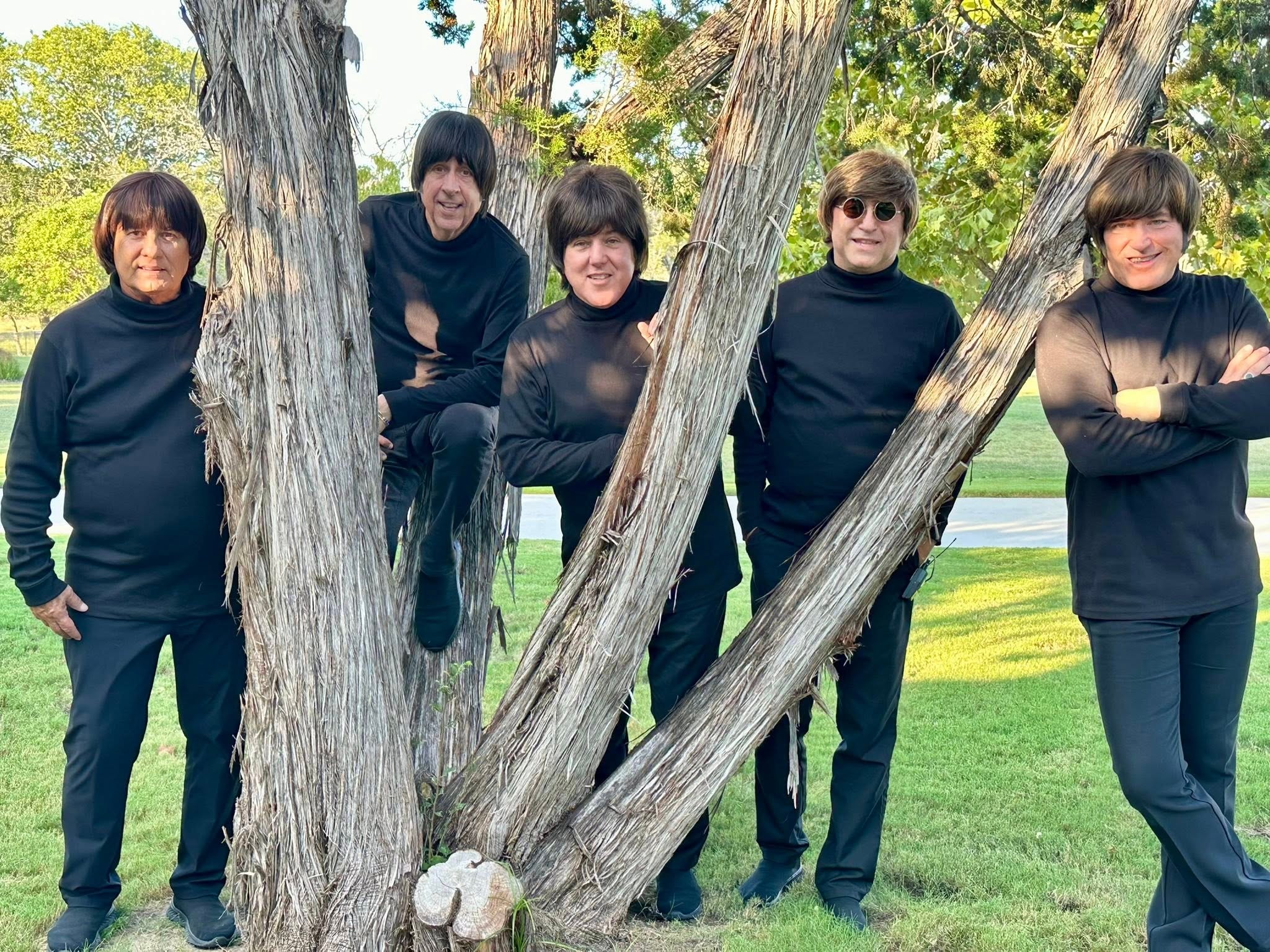 The Fab 5 in black turtlenecks posing by a large tree