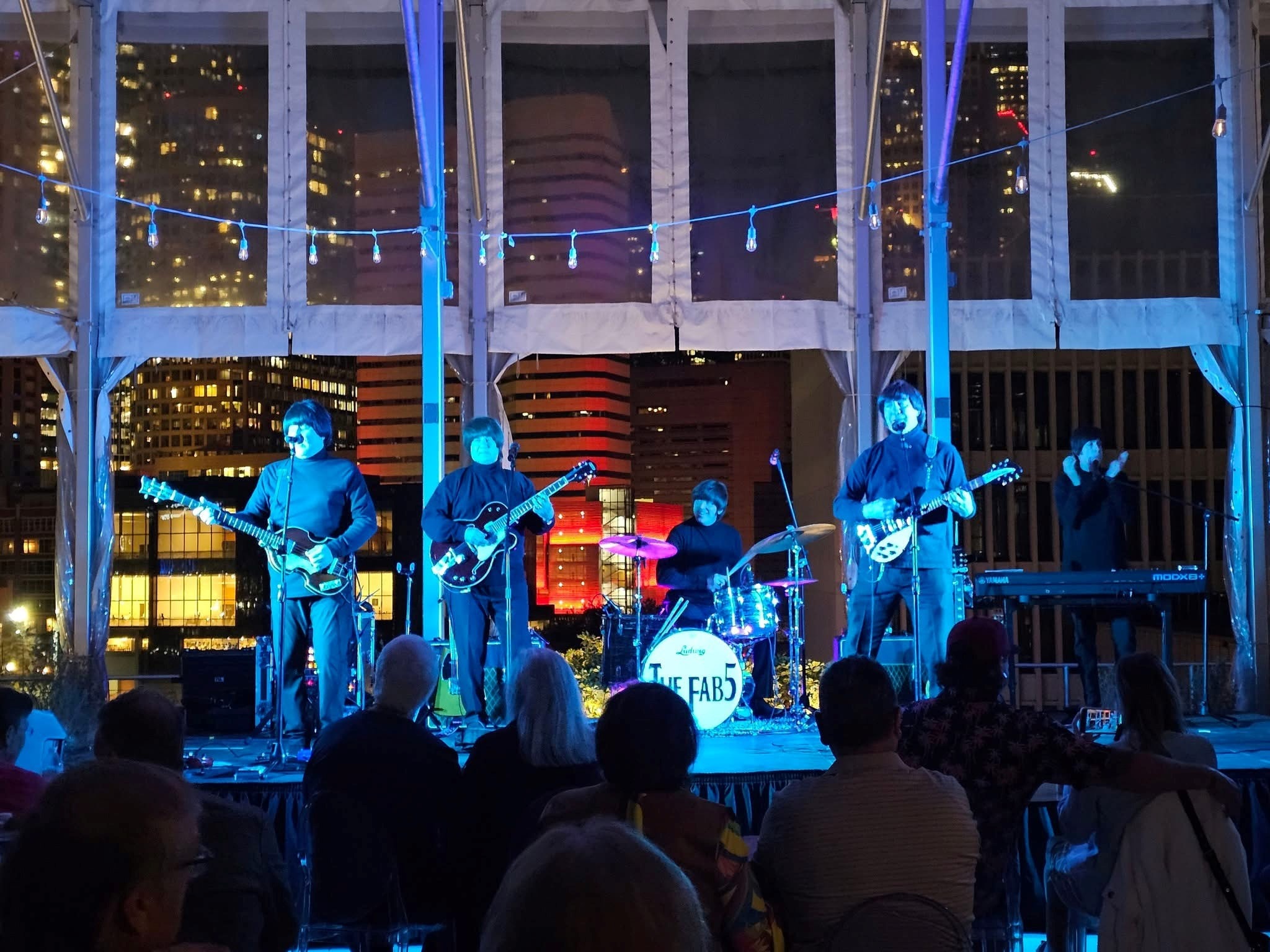 The Fab 5 performing on rooftop stage with city skyline at night