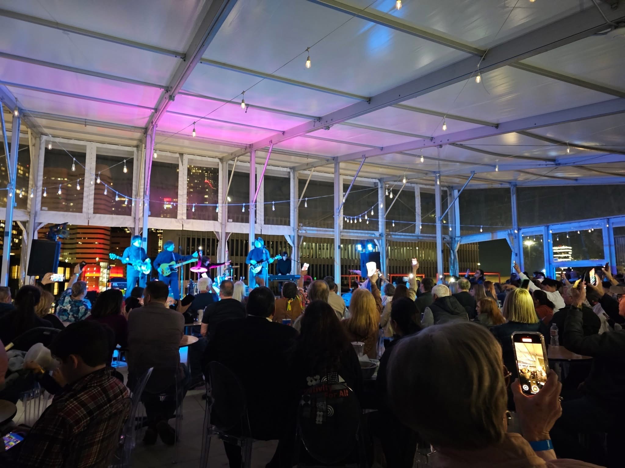 The Fab 5 performing under tent with crowd holding up phones