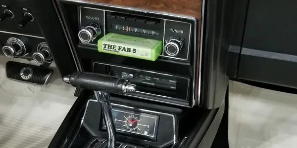 The Fab 5 Greatest Hits cassette tape in a vintage car stereo